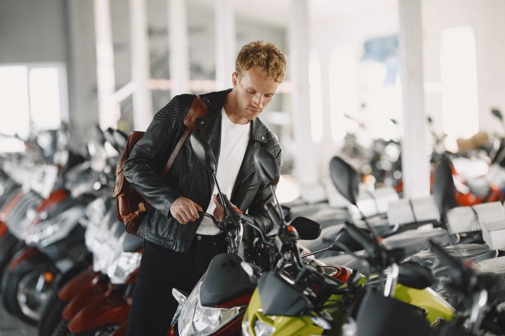 Joven mirando varias motos antes de comprar una. Fuente: iStock / prostooleh