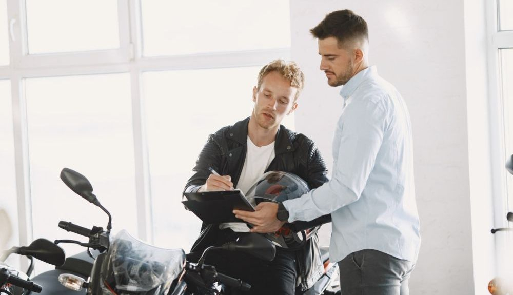 Joven firmando la compra de una de las motos matriculadas en 2021. Fuente: iStock / prostooleh Joven firmando la compra de una de las motos matriculadas en 2021. Fuente: iStock / prostooleh