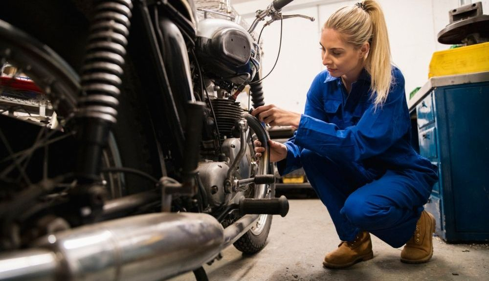 Mujer reparando el motor de una moto. Fuente: iStock.com/SolStock Mujer reparando el motor de una moto. Fuente: iStock.com/SolStock