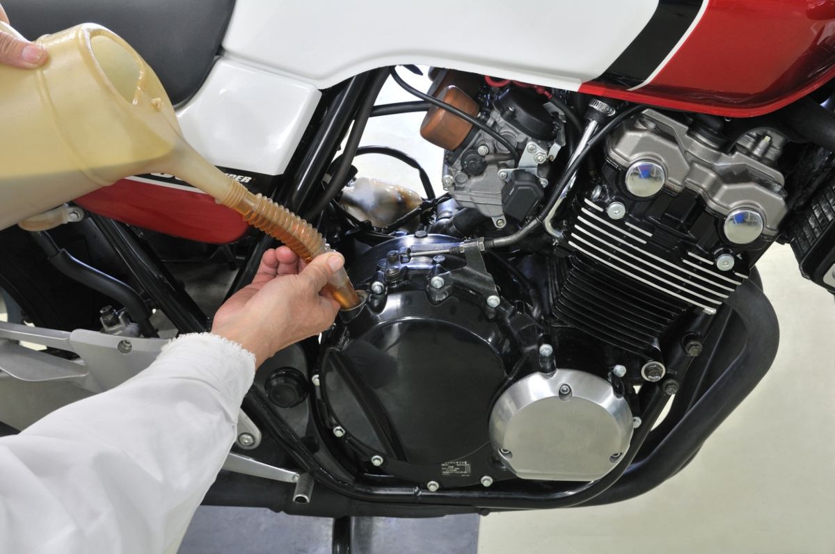 Añadiendo aceite, que también sirve para la refrigeración, a una moto. Fuente: iStock / dreamnikon