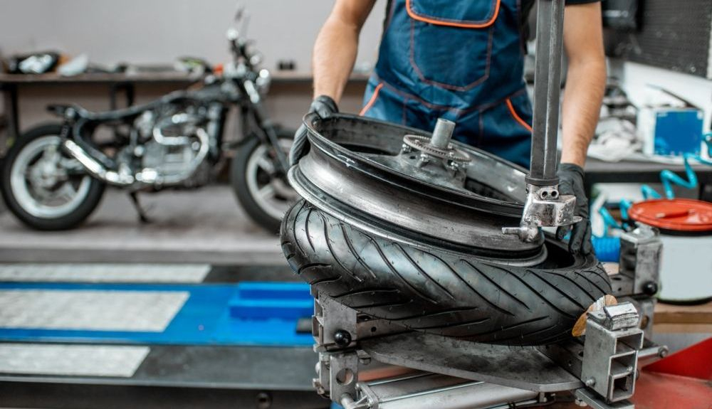 Mecánico arreglando una llanta de una moto. Fuente: iStock.com/ RossHelen Mecánico arreglando una llanta de una moto. Fuente: iStock.com/ RossHelen
