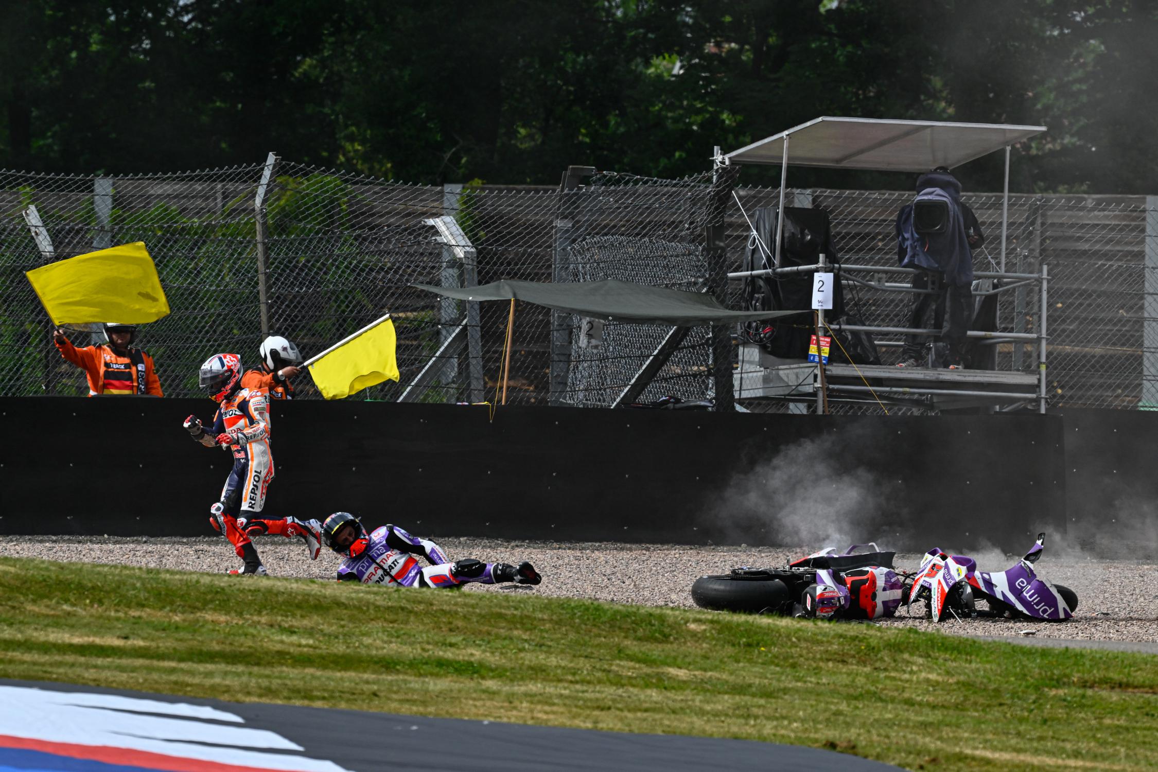 Marc Márquez corre hacia el pit lane mientras Johann Zarco todavía está en el suelo.