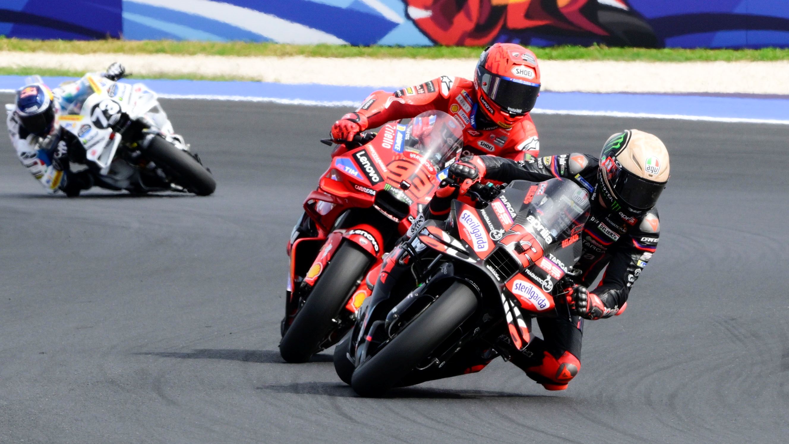 Marco Bezzecchi con Marc Márquez pegado y Álex Márquez al fondo, MotoGP San Marino 2025