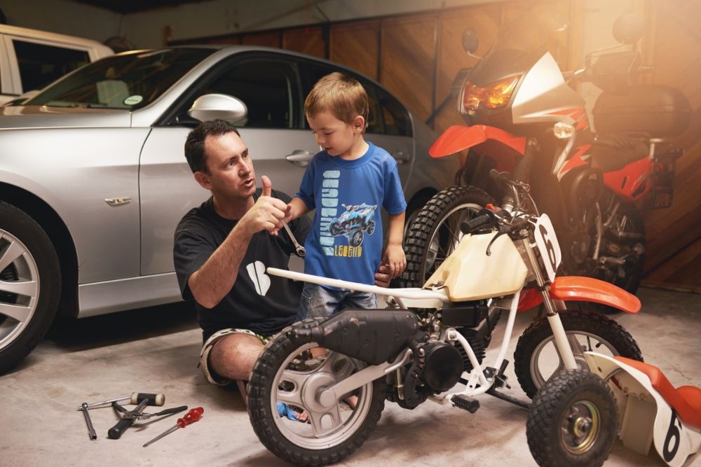 Un padre y su hijo arreglando la moto del niño. Fuente: iStock/PeopleImages Un padre y su hijo arreglando la moto del niño. Fuente: iStock/PeopleImages