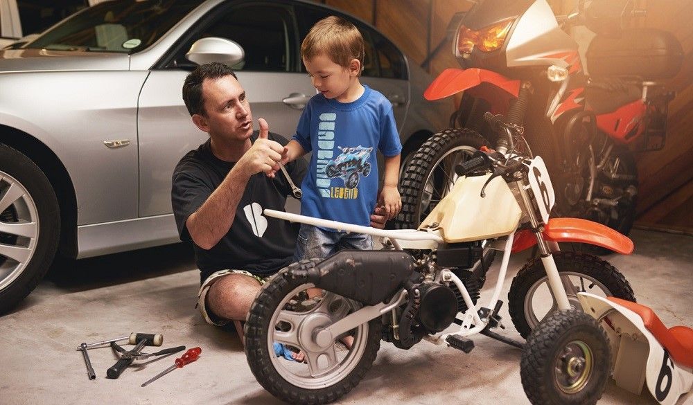 Un adulto enseñando a un niño la mecánica de la minimoto. Fuente: iStock/PeopleImages Un adulto enseñando a un niño la mecánica de la minimoto. Fuente: iStock/PeopleImages