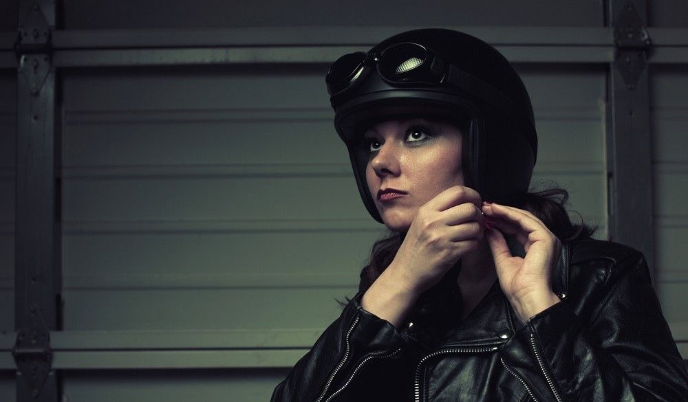 Conductora realizando la acción de ajustar el casco de la moto. Fuente: iStock/Marilyn Nieves