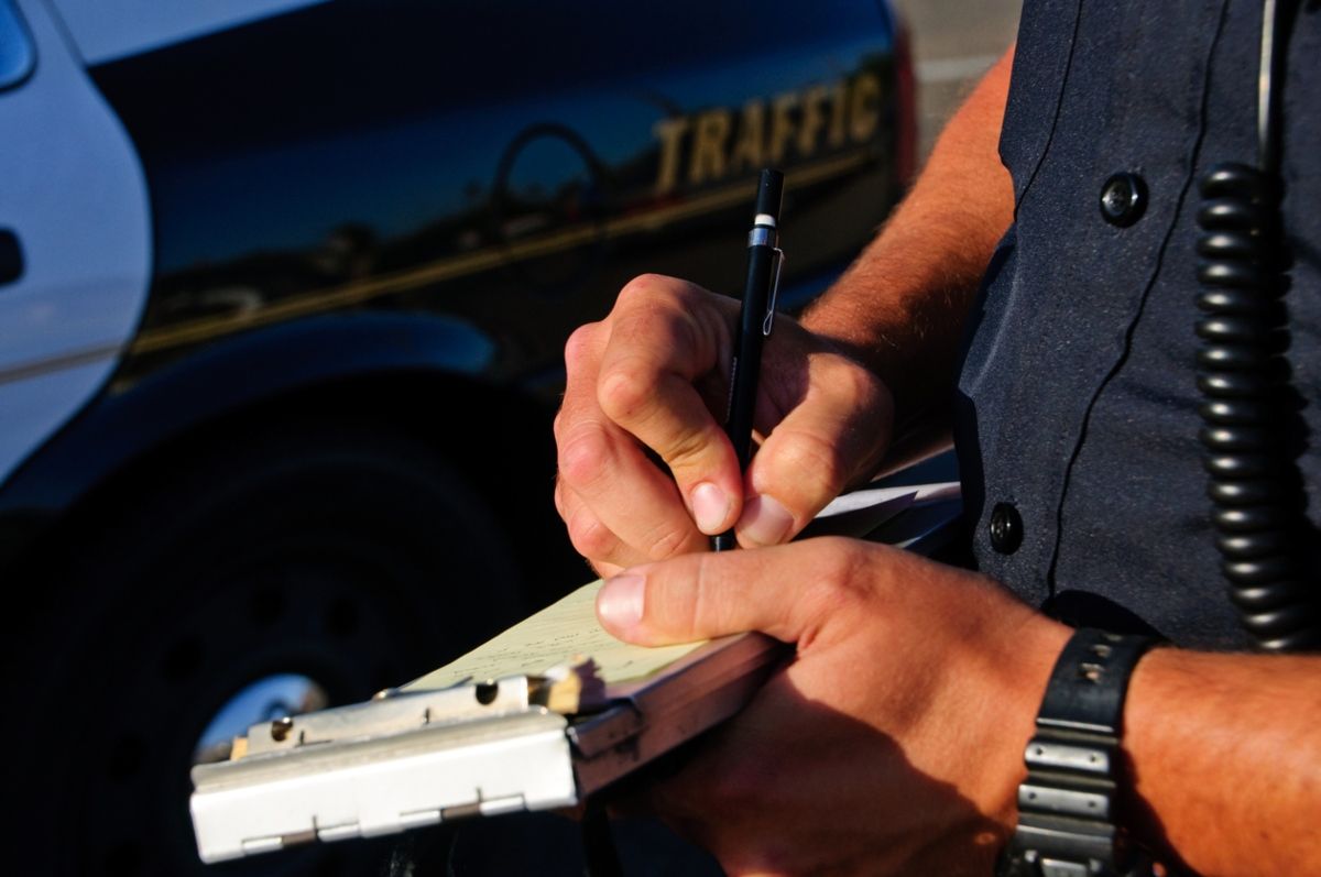 Agente poniendo una de las sanciones de la DGT. Fuente: iStock / aijohn784