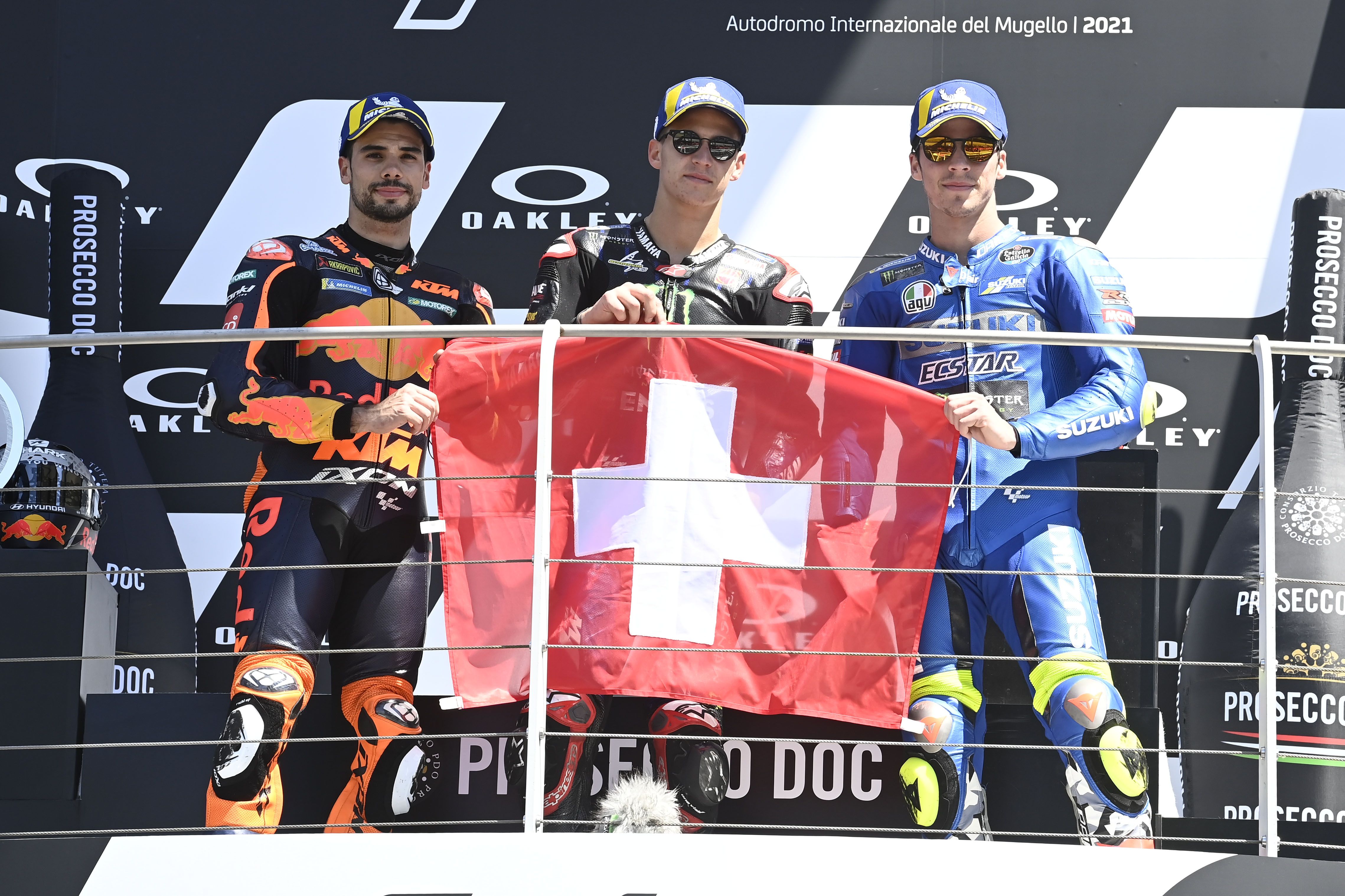 Fabio Quartararo, Miguel Oliveira y Joan Mir con la bandera suiza en honor a Jason Dupasquier