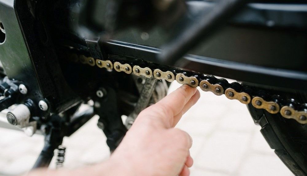 Un hombre comprueba la tensión de la cadena en la motocicleta. Fuente: iStock/djedzura Un hombre comprueba la tensión de la cadena en la motocicleta. Fuente: iStock/djedzura