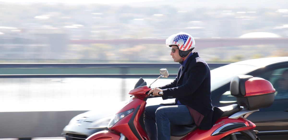 Joven en una moto donde se puede ver su baúl trasero. Fuente: iStock / AlexLinch.