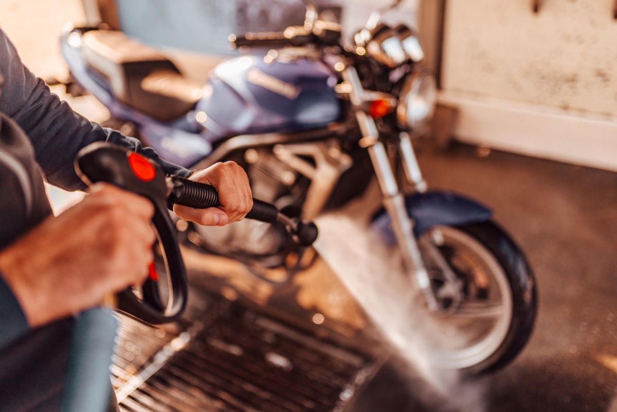 Uso de la manguera a presión para limpiar la moto. Fuente: iStock / nortonrsx.