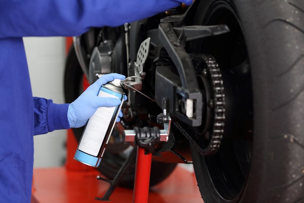 Lubricando la cadena tras limpiar la moto. Fuente: iStock / AntonioGuillem Lubricando la cadena tras limpiar la moto. Fuente: iStock / AntonioGuillem