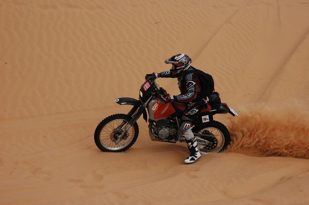 Moto recorriendo el desierto, escenario del Rally de los Faraones. Fuente: iStock/leonardodesign21