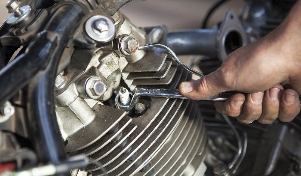 Desenroscando una bujía de la moto. Fuente: iStock/MagMos