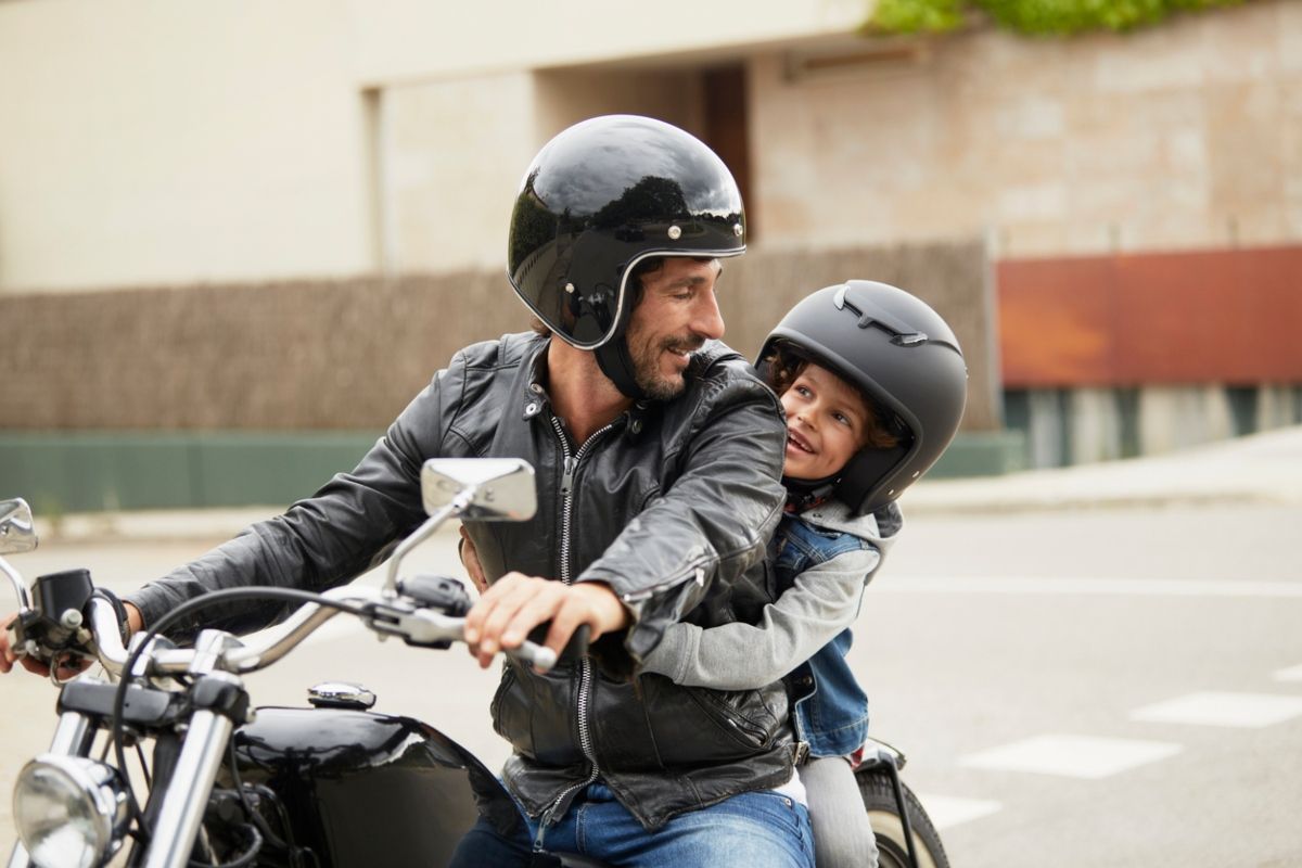 Padre con su hija, que debe tener la edad mínima para ir en una moto. Fuente: iStock / Morsa Images