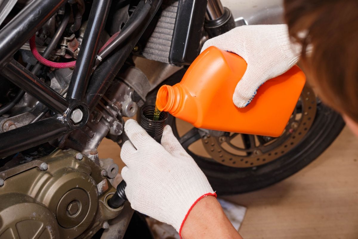 Motorista cambiando el aceite de la moto. Fuente: iStock / Aleksey Shvedov