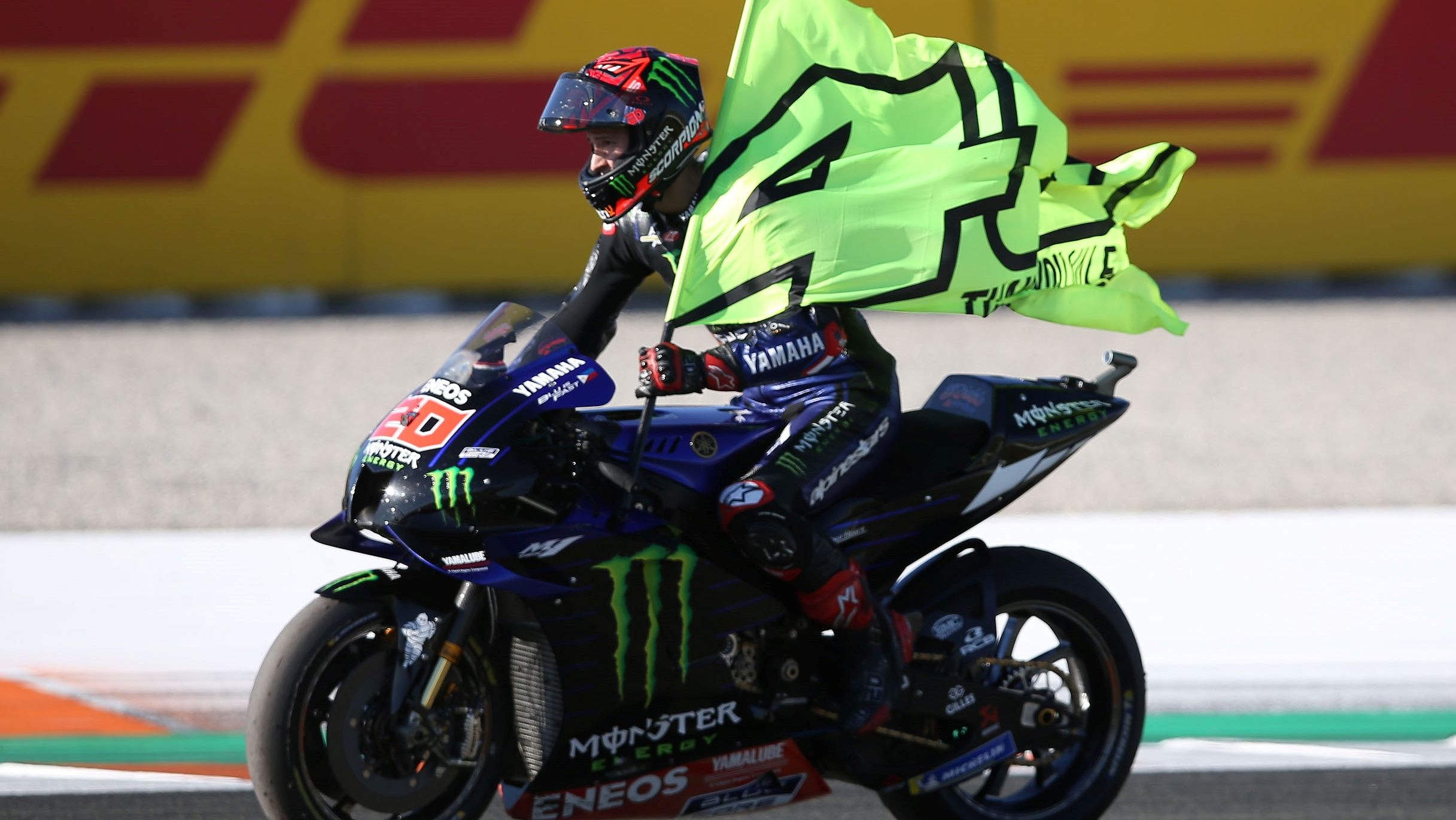 Fabio Quartararo sobre la Yamaha paseando una bandera con el 46 de Valentino Rossi